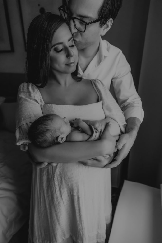 black and white image of mother and father holding their newborn 