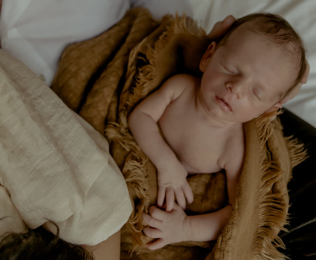 newborn sleeping wrapped in brown blanket
