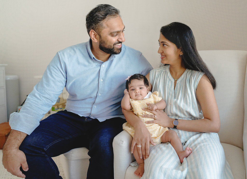 long island newborn session two parents holding their baby girl on the couch.